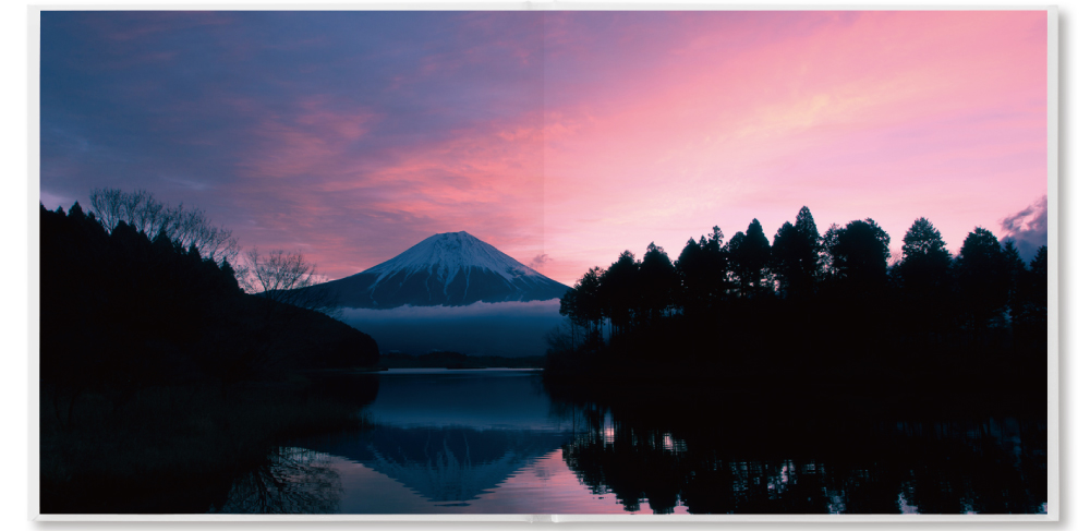 見開き2ページに継ぎ目なく広がる夕焼けの富士山と湖の写真