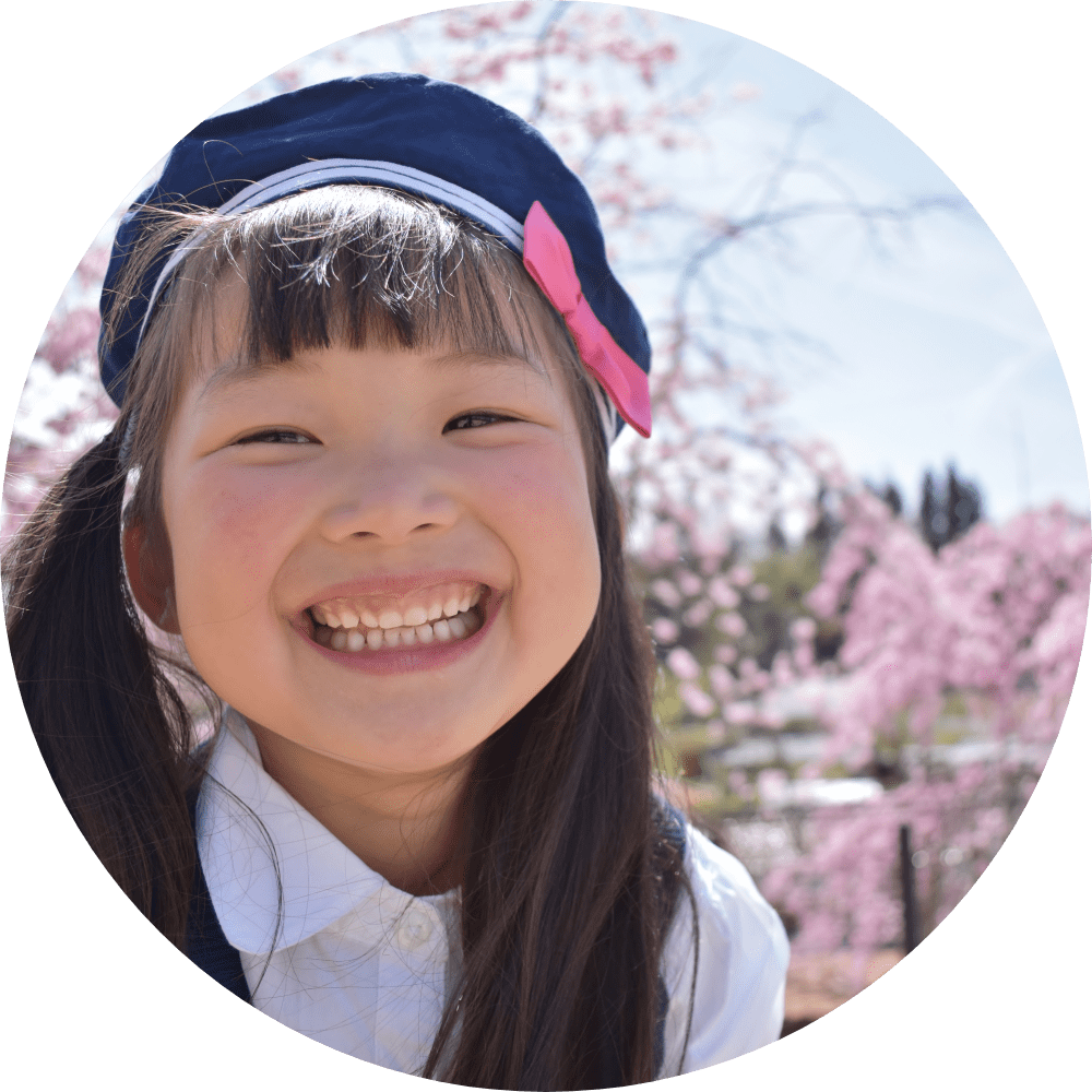 桜の前で笑顔の入園入学の女の子